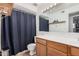 Well-lit bathroom featuring wood vanity with a white countertop, large mirror and a blue shower curtain at 11403 N 57Th Dr, Glendale, AZ 85304