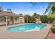 Sparkling pool with a rock waterfall feature, surrounded by lush landscaping and a brick patio at 11431 N 37Th Pl, Phoenix, AZ 85028