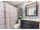 Bathroom features a vanity with a dark cabinet, neutral shower curtain and grass detail for a fresh look at 12162 W Dreyfus Dr, El Mirage, AZ 85335