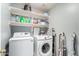 Bright laundry room with modern washer and dryer units, storage shelves, and an ironing board at 12162 W Dreyfus Dr, El Mirage, AZ 85335