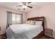 The main bedroom has a light pink wall, a ceiling fan, and a decorative white blanket at 12162 W Dreyfus Dr, El Mirage, AZ 85335