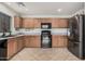 Well-lit kitchen featuring wood cabinets, black appliances, and neutral tile flooring at 12530 W Jackson St, Avondale, AZ 85323