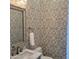 A stylish powder room with patterned wallpaper, a marble countertop, and decorative mirror at 13613 N 76Th St, Scottsdale, AZ 85260