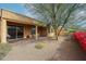 Backyard featuring a covered patio, neutral rock landscaping, mature trees, and a partial view of the fence line at 17555 W Glenhaven Dr, Goodyear, AZ 85338