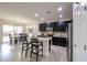 Modern kitchen open to dining area features dark cabinets, stainless appliances, granite counters, and breakfast bar at 17555 W Glenhaven Dr, Goodyear, AZ 85338