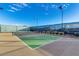 Well-maintained tennis court with net, surrounded by green hedges under a bright blue sky at 17555 W Glenhaven Dr, Goodyear, AZ 85338