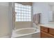 Large tub sits beneath a window of glass blocks in this lovely bathroom at 19025 E Raven Dr, Queen Creek, AZ 85142