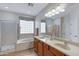 Bright bathroom featuring double sinks, large mirror, soaking tub, and glass-enclosed shower at 19025 E Raven Dr, Queen Creek, AZ 85142