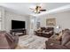 Cozy living room featuring a fireplace, ceiling fan, and comfortable brown leather seating at 19025 E Raven Dr, Queen Creek, AZ 85142