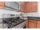 Stainless steel stove with a black cooktop, granite countertops, and wooden cabinets at 2075 S Ponderosa Dr, Gilbert, AZ 85295