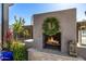 Outdoor fireplace with a decorative wreath and stone accents surrounded by lush greenery at 21413 N 59Th St, Phoenix, AZ 85054