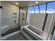 Bright bathroom showcasing modern shower with black hardware, and a soaking tub with skylight at 26637 S New Town Dr, Sun Lakes, AZ 85248