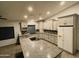 Modern kitchen boasts granite countertops, stainless steel appliances, white cabinets, and a central island cooktop at 26637 S New Town Dr, Sun Lakes, AZ 85248