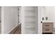 A sleek and modern bathroom featuring an open, white shelving system near a wooden vanity with black hardware at 3009 W Alice Ave, Phoenix, AZ 85051