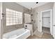 Bright bathroom featuring a glass block window, soaking tub, and glass-enclosed shower at 318 E Gail Dr, Gilbert, AZ 85296