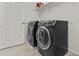 This laundry room has black appliances, tiled floors, and a white shelving unit above the appliances at 3263 S Miller Dr, Chandler, AZ 85286