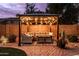 Cozy backyard gazebo features comfortable seating and warm string lights against a brick wall and patio at 3274 E Isaiah Ct, Gilbert, AZ 85298