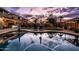 A beautiful swimming pool reflecting a colorful dusk sky, surrounded by well-manicured landscaping and a cozy gazebo at 3274 E Isaiah Ct, Gilbert, AZ 85298