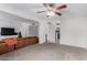 Cozy living room featuring neutral carpet, ceiling fan, and an inviting brown leather couch at 4022 W Kaler Dr, Phoenix, AZ 85051