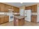 Spacious kitchen featuring white appliances, wood cabinets and a center island at 44983 W Sage Brush Dr, Maricopa, AZ 85139