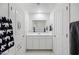 Bright bathroom featuring dual linen closets, modern vanity, and a large mirror at 47558 W Mellen Ln, Maricopa, AZ 85139