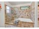 Neutral bathroom features a bathtub and a glass shower with decorative tile and a small plant in the window at 5951 E Inglewood St, Mesa, AZ 85205