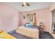 Cozy bedroom with pink walls, carpet and a bed with floral patterned bedding and a window for natural light at 5951 E Inglewood St, Mesa, AZ 85205