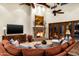 Comfortable living room with stone fireplace, high ceiling with wooden beams, and ample seating at 7363 E Lower Wash Pass, Scottsdale, AZ 85266