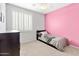 A bedroom with a single bed, pink accent wall, and window with shutters at 7387 W Remuda Dr, Peoria, AZ 85383