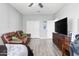 Bedroom boasting hardwood floors, white trim and doors, a ceiling fan, and a large TV at 7387 W Remuda Dr, Peoria, AZ 85383