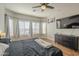 Bright primary bedroom with a ceiling fan, wood floors, and a large TV at 7525 W Springfield Way, Florence, AZ 85132