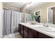 Bright bathroom with a double sink vanity, a large mirror, and a shower with a curtain at 7840 W Bonitos Dr, Phoenix, AZ 85035