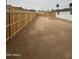 A expansive dirt backyard with a newly installed wood fence and renovated white home exterior at 7955 W Mackenzie Dr, Phoenix, AZ 85033