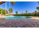 Backyard pool with brick patio, bordered by a green lawn, flowers and tall trees at 8005 N Via De Lago --, Scottsdale, AZ 85258