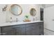 Bright bathroom features a gray vanity with marble countertop and dual sinks with round wood-framed mirrors at 8709 E Mackenzie Dr, Scottsdale, AZ 85251