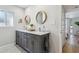 Bright bathroom features a gray vanity with marble countertop and dual sinks with round wood-framed mirrors at 8709 E Mackenzie Dr, Scottsdale, AZ 85251