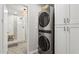 Modern laundry room with stacked washer and dryer and decorative tile with bathroom view at 8709 E Mackenzie Dr, Scottsdale, AZ 85251