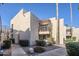 Stylish stucco two-story condo with a private balcony, lush landscaping, and mature palm trees at 9275 E Mission Ln # 206, Scottsdale, AZ 85258