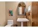 Well-lit powder room with a pedestal sink, decorative mirror, and gold fixtures at 9280 E Thompson Peak Pkwy # 25, Scottsdale, AZ 85255