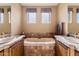 Bright bathroom with dual sinks, soaking tub, tile accents, and soft natural light from two windows at 9280 E Thompson Peak Pkwy # 25, Scottsdale, AZ 85255