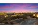 Nighttime neighborhood view highlighting desert vegetation, residential architecture, and the illuminated cityscape in distance at 9280 E Thompson Peak Pkwy # 25, Scottsdale, AZ 85255