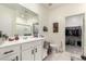 Bright bathroom with double sinks, white cabinets, and a view into the walk-in closet at 9539 W Agora Ln, Tolleson, AZ 85353