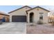 Inviting home featuring a two-car garage, desert landscaping, and an arched entryway at 9539 W Agora Ln, Tolleson, AZ 85353