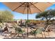 Backyard patio with green metal chairs, shade umbrella, desert landscaping and mountain views at 100 N Lazy Fox Rd # 3, Wickenburg, AZ 85390