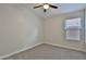 A bright bedroom features a ceiling fan, a window, neutral walls, and carpet flooring at 10353 W Atlantis Way, Tolleson, AZ 85353