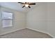A bright bedroom features a ceiling fan, a large window, neutral walls, and carpet flooring at 10353 W Atlantis Way, Tolleson, AZ 85353