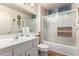 Bright bathroom featuring white vanity, toilet, and a shower-tub combo with glass doors at 13602 W Ballad Dr, Sun City West, AZ 85375