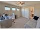 Bright bedroom with a ceiling fan, a workspace with desk, couch, and a closet, featuring ample natural light at 13641 W Solano Dr, Litchfield Park, AZ 85340