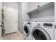 Laundry room offers modern washer and dryer, plus shelving for organizing supplies at 17028 W Cocopah St, Goodyear, AZ 85338