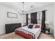Bedroom featuring a black metal frame bed, stylish chandelier, and windows with dark curtains at 2067 N Marketside Ave, Buckeye, AZ 85396